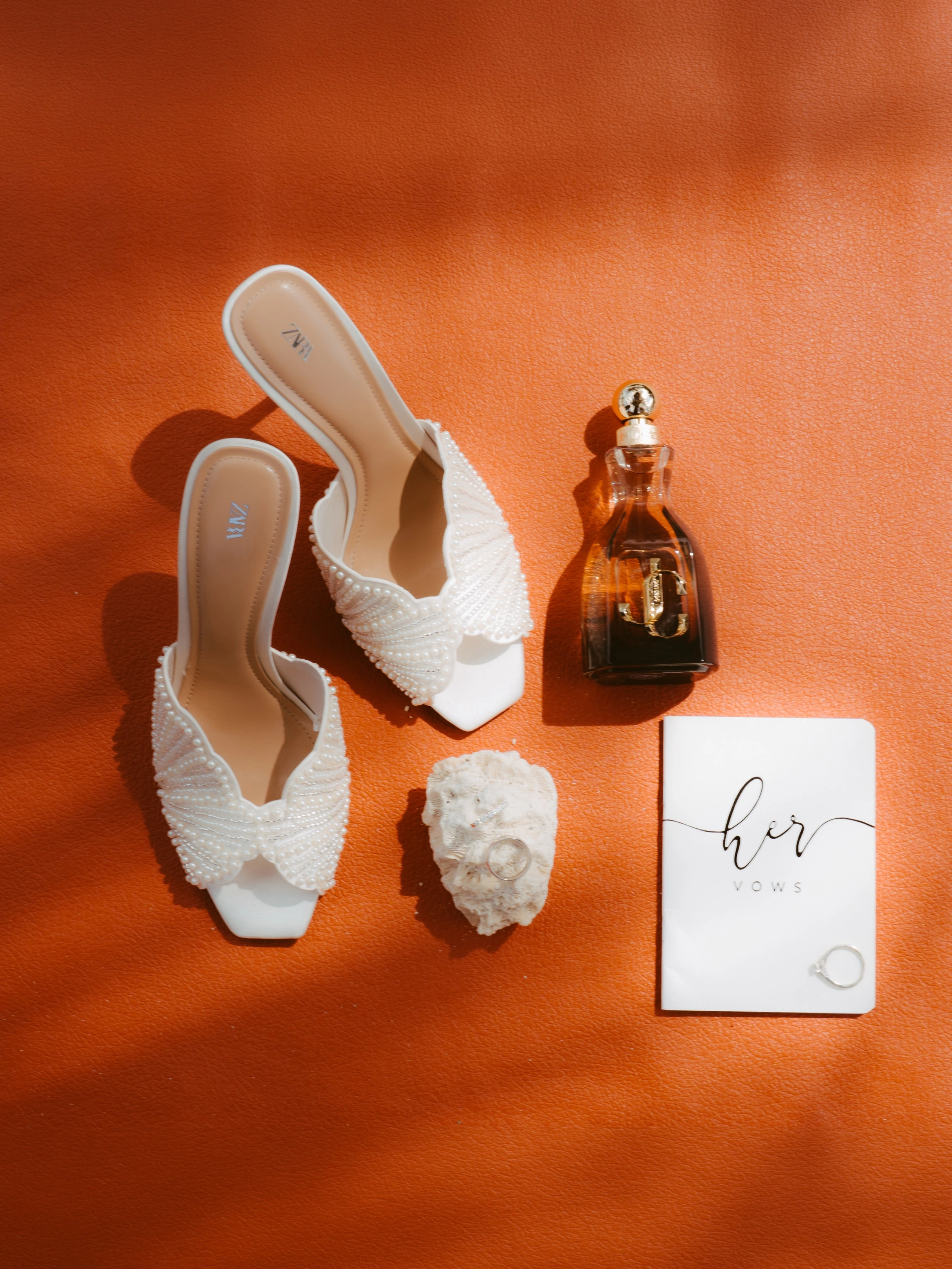 Zapatos blancos y detalles de boda sobre una superficie naranja